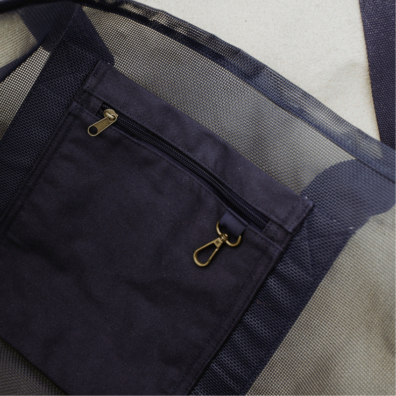 Close-up of the high-quality features of the Sande Kids Beach Hauler mesh beach bag in Deep Sea Navy. Showcases the internal canvas pocket for valuables and a handy key clip, along with the durable PVC mesh fabric and thick cotton straps.