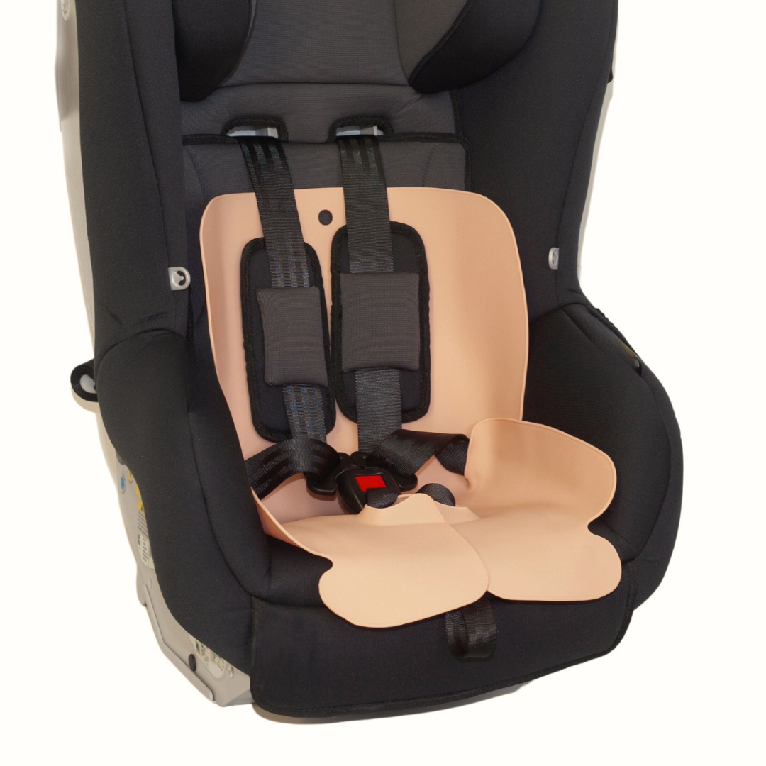The Sande Kids™ waterproof car seat and pram liner in Coral Pink is shown in a harnessed forward-facing car seat.