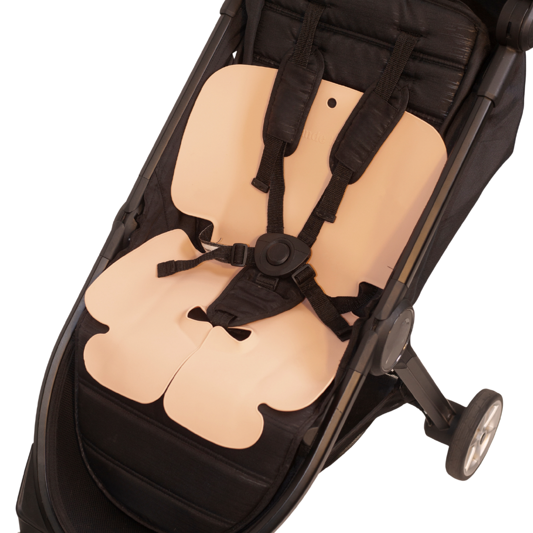 The Sande Kids™ waterproof car seat and pram liner in coral pink is shown in a pram or stroller.