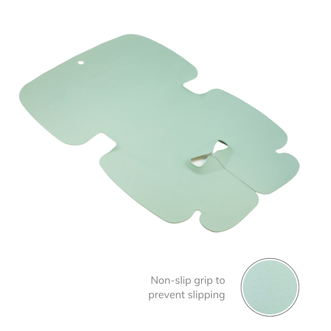 The Sande Kids™ waterproof car seat and pram liner in Seafoam Green is shown laid out flat, featuring a molded design around the crotch buckle for enhanced comfort and security. A small inset image highlights the non-stick grip on the back, designed to prevent slipping and provide a secure, stable fit.