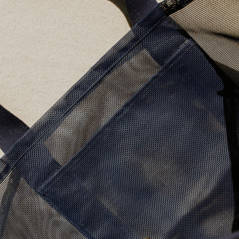 Close-up of the high-quality features of the Sande Kids Beach Hauler - Mini, a large mesh beach bag in Deep Sea Navy. Showcases the large internal mesh pocket for extra storage, along with the durable PVC mesh fabric and thick cotton straps.