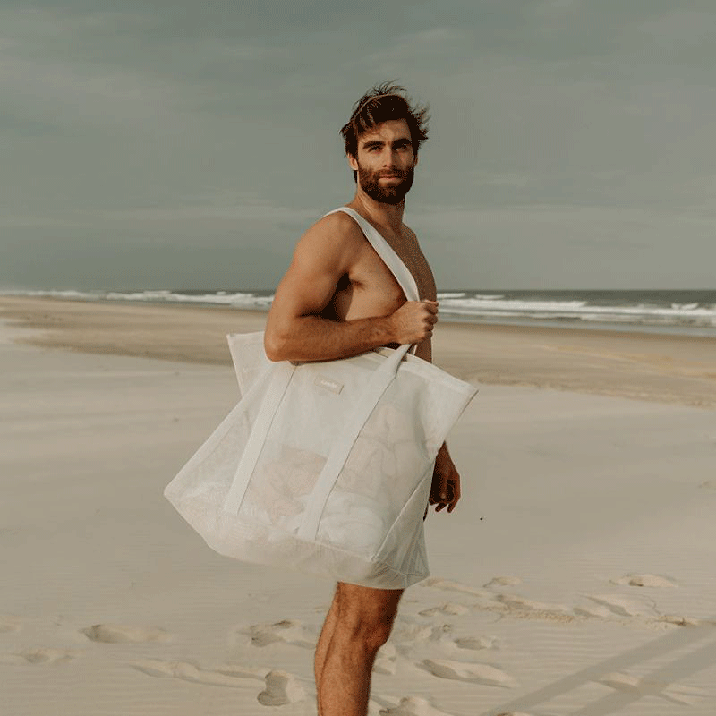 Dad carrying the oversized Sande Kids Beach Hauler mesh beach bag, showcasing its spacious design and durability for family beach outings.