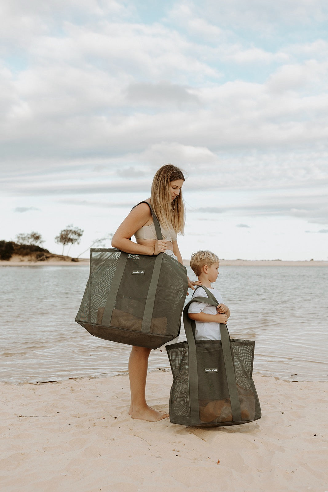 Mother and son at the beach. Mum carries the Sande Kids Beach Hauler in dark green, son carries the Beach Hauler - Mini in dark green.