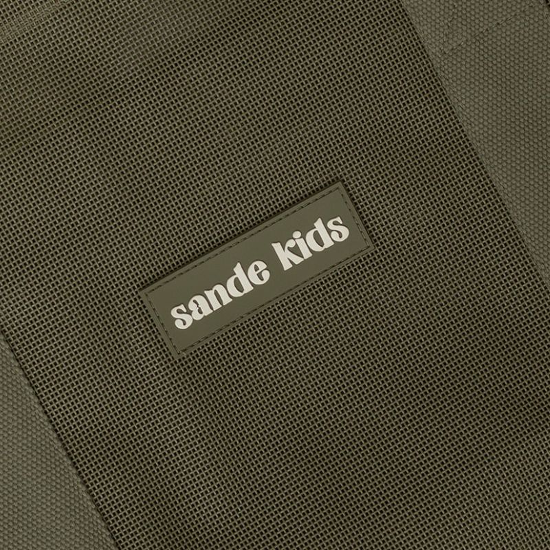 Close-up of the Sande Kids silicone logo on Pandanus Green PVC-coated mesh, featuring cotton strap detailing.