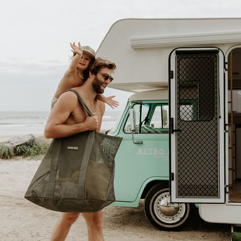 Tall man with a young boy carrying the Sande Kids orginal oversized mesh beach bag in sage green.
