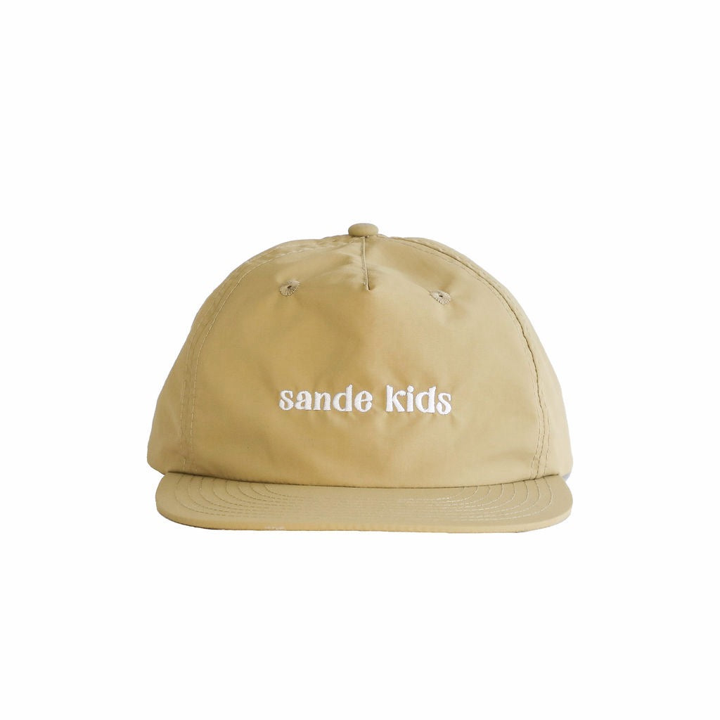 A beige cap made from waterproof nylon fabric, shown from the front. The cap features the Sande Kids™ logo embroidered in white on the front.