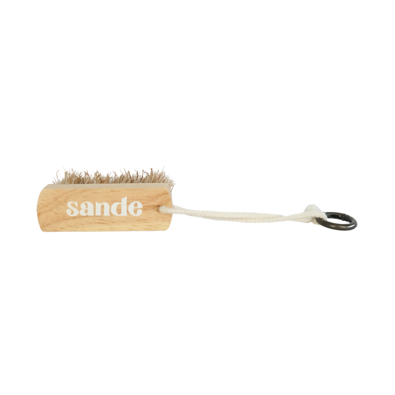 Sande wooden sand removal brush with natural bristles and rope handle, photographed on a white studio background.