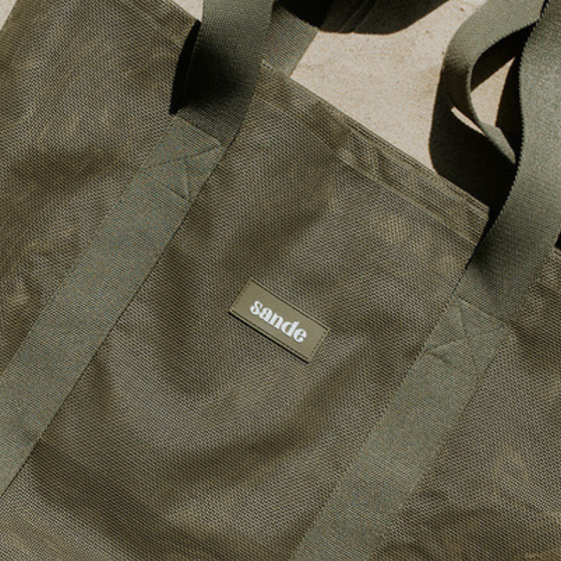 Sande Kids original mesh beach bag in Pandanus green showcasing silicone label feature.
